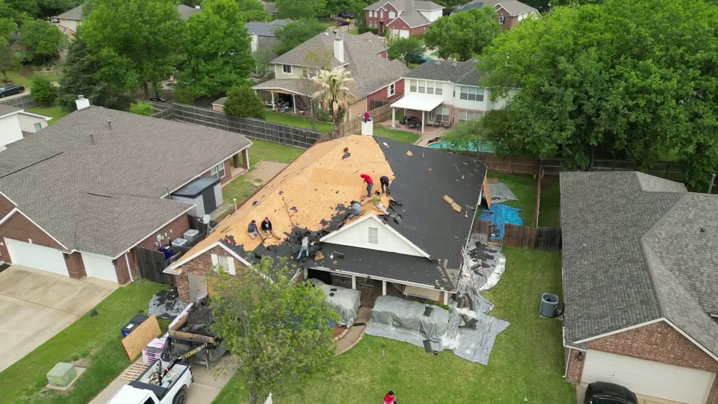 Bright Roofing crew tearing off an old roof, photographed by drone