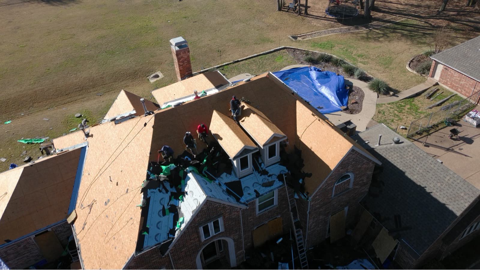 Drone photo of a Bright Roofing crew tearing off a roof in Flower Mound, decking exposed
